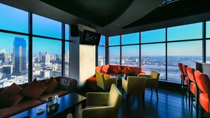 Un salón moderno con vistas a la ciudad, que incluye un sofá, sillas y una mesa con una taza de café.