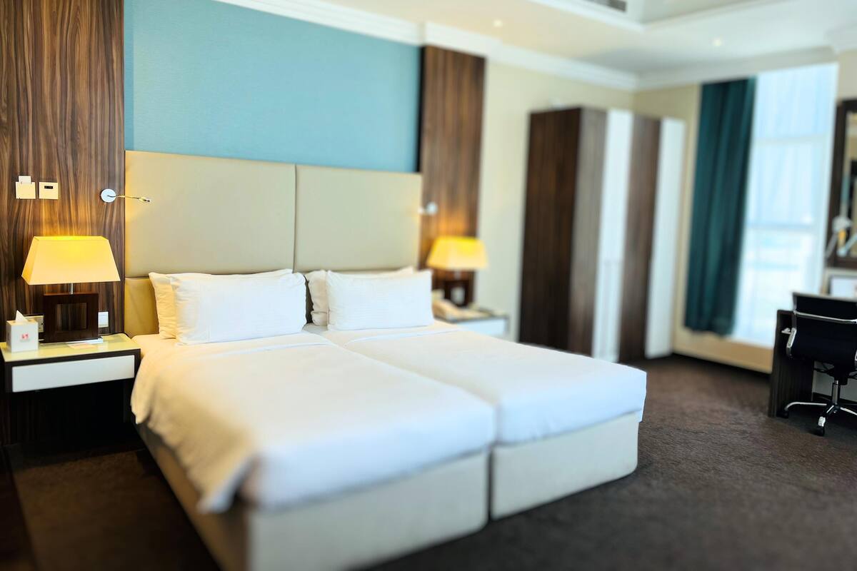 A hotel room with a large bed, two bedside tables with lamps, a desk, and a chair.