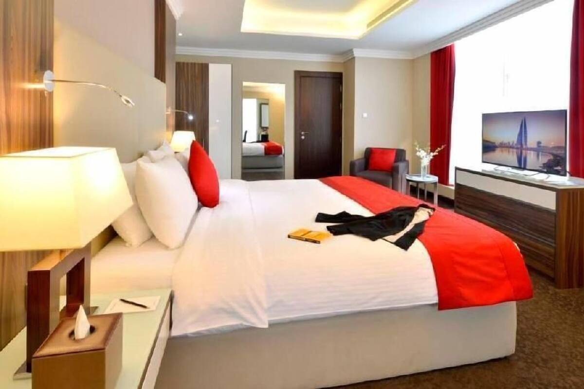 A hotel room with a large bed, a TV, a desk, and a view of a bridge.