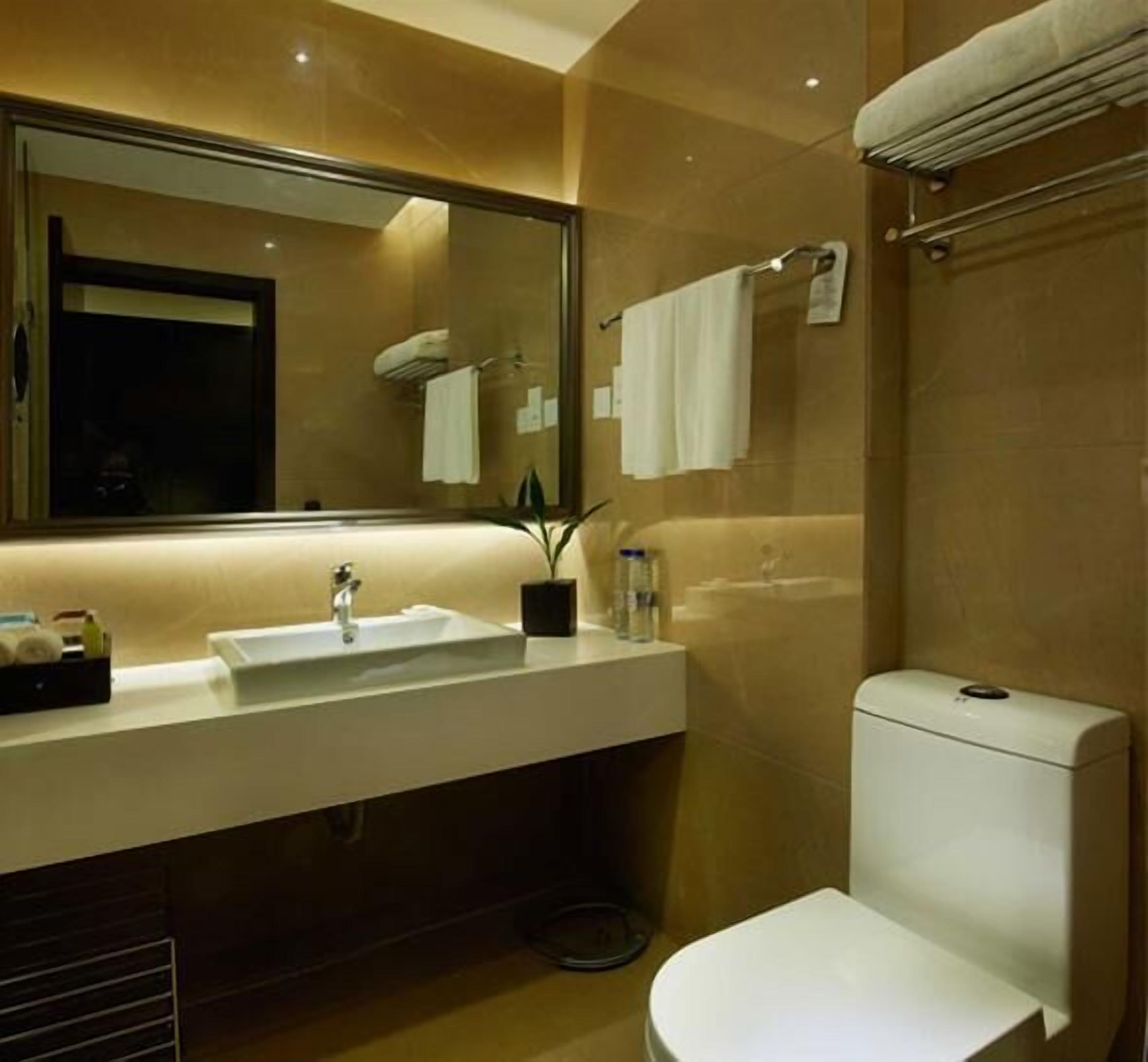 A modern bathroom with a large mirror, a sink, a toilet, and a towel rack.