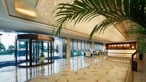 A lobby with a glass revolving door, a reception desk, and a large chandelier.