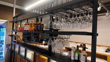 A bar area with shelves of liquor bottles and a rack of wine glasses.