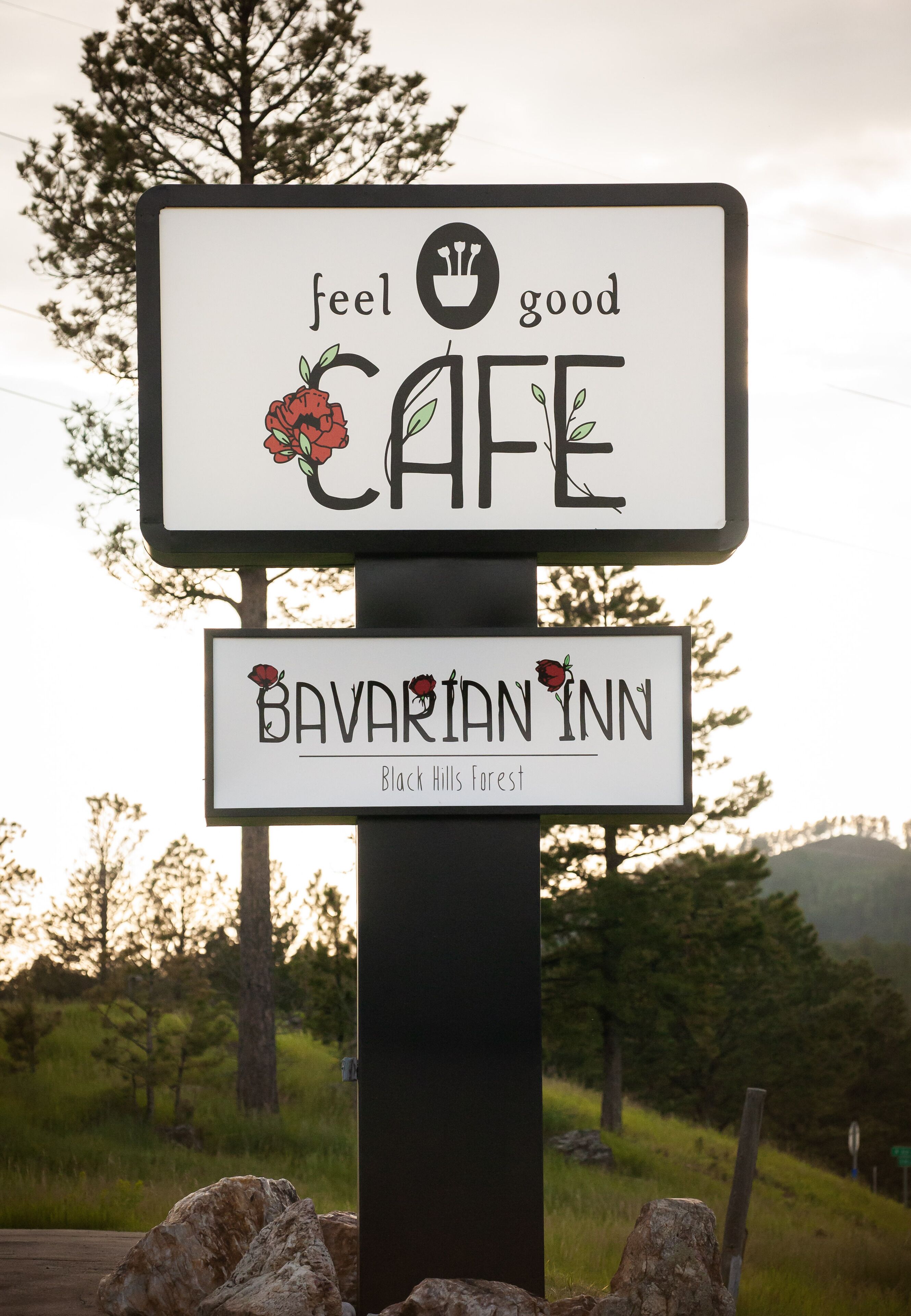A sign for Bavarian Inn with a 'feel good cafe' message and a rose illustration.