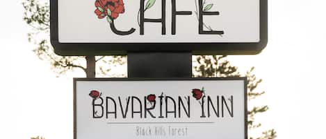 A sign for Bavarian Inn with a 'feel good cafe' message and a rose illustration.