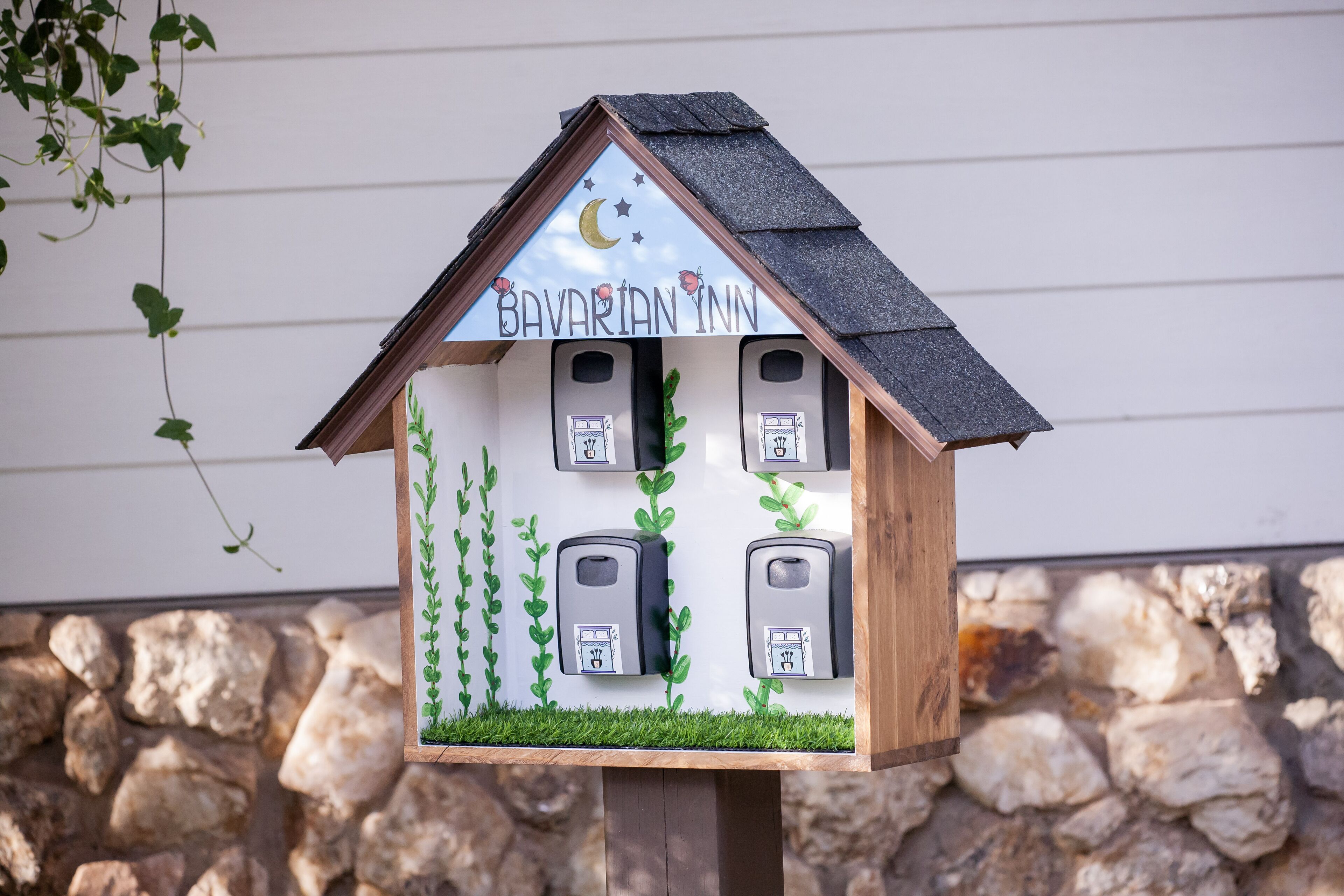 Un comedero de madera con la inscripción 'Bavarian Inn' y un diseño de luna y estrellas en el techo.
