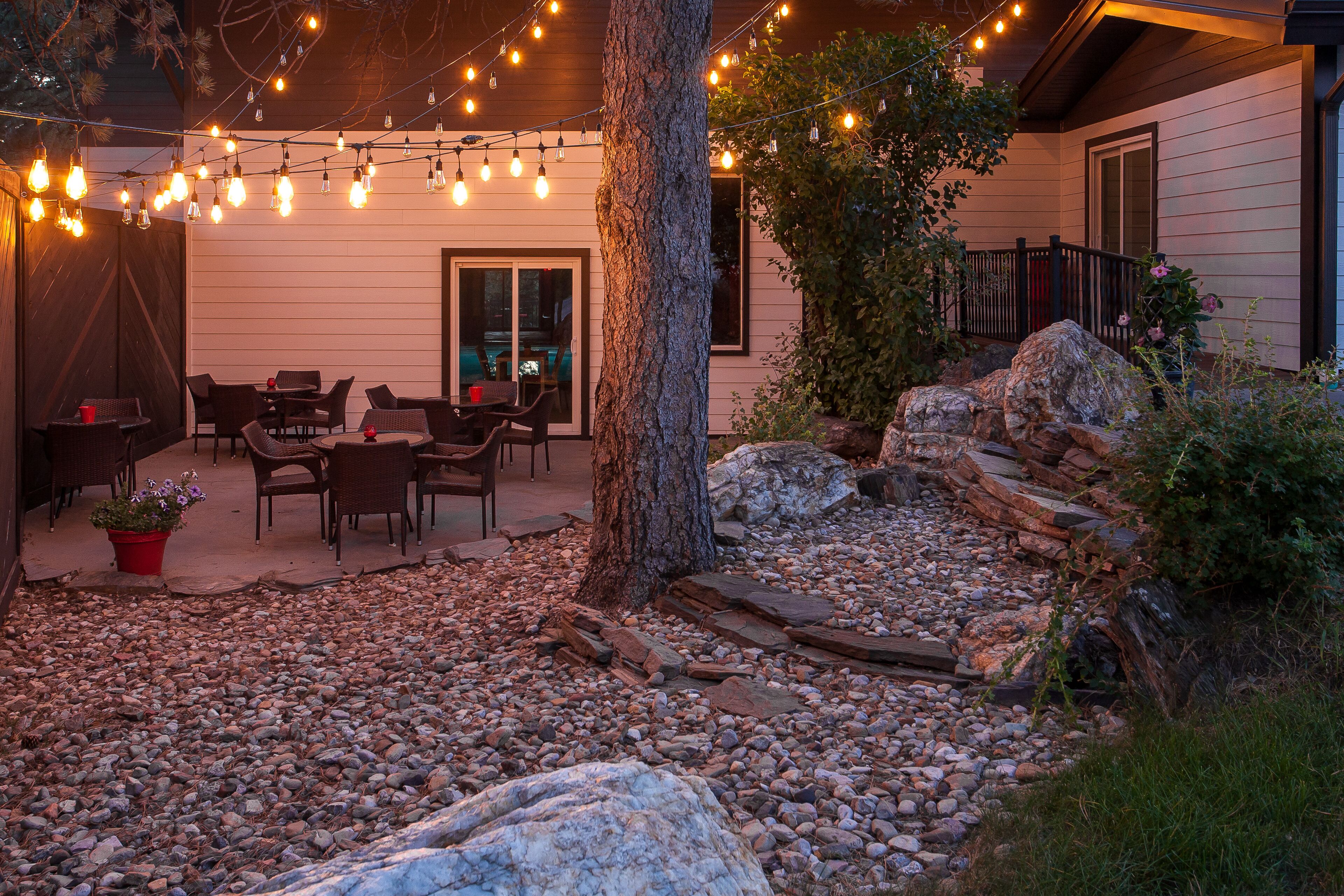An outdoor patio area with string lights, seating, and a stone pathway.