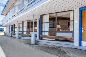 A modern building with large windows, a wooden bench outside, and a blue door.
