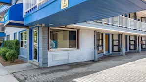 Ein Hotel mit blauer Fassade, einem Warnschild für eine Höhe von 2,1 Metern und einem überdachten Außenbereich mit Balkon.