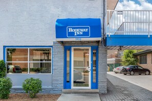 A Rodeway Inn with a blue awning and a brick facade.