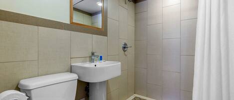 Un baño con inodoro, lavabo y ducha.