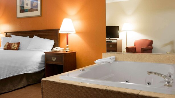 Ein Hotelzimmer mit einem großen Bett, einer Sitzecke mit einem Sessel, einer Badewanne und einem Fernseher.