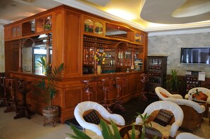 A bar area with wooden cabinetry, bar stools, and a television mounted on the wall. - City Angkor Hotel (Siem Reap)