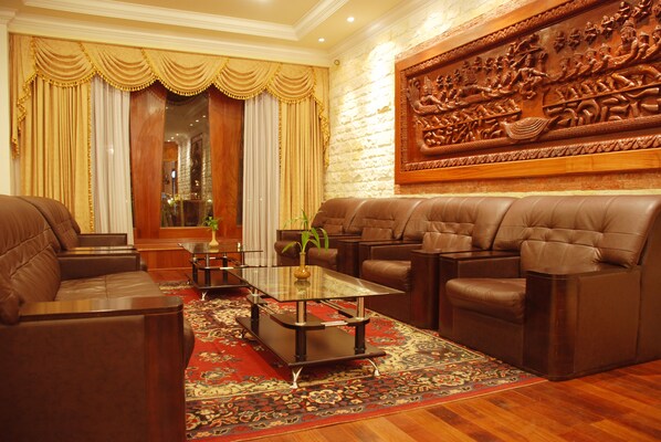 Amplio salón con sofás de cuero, una mesa de centro de vidrio y un gran relieve decorativo en la pared.