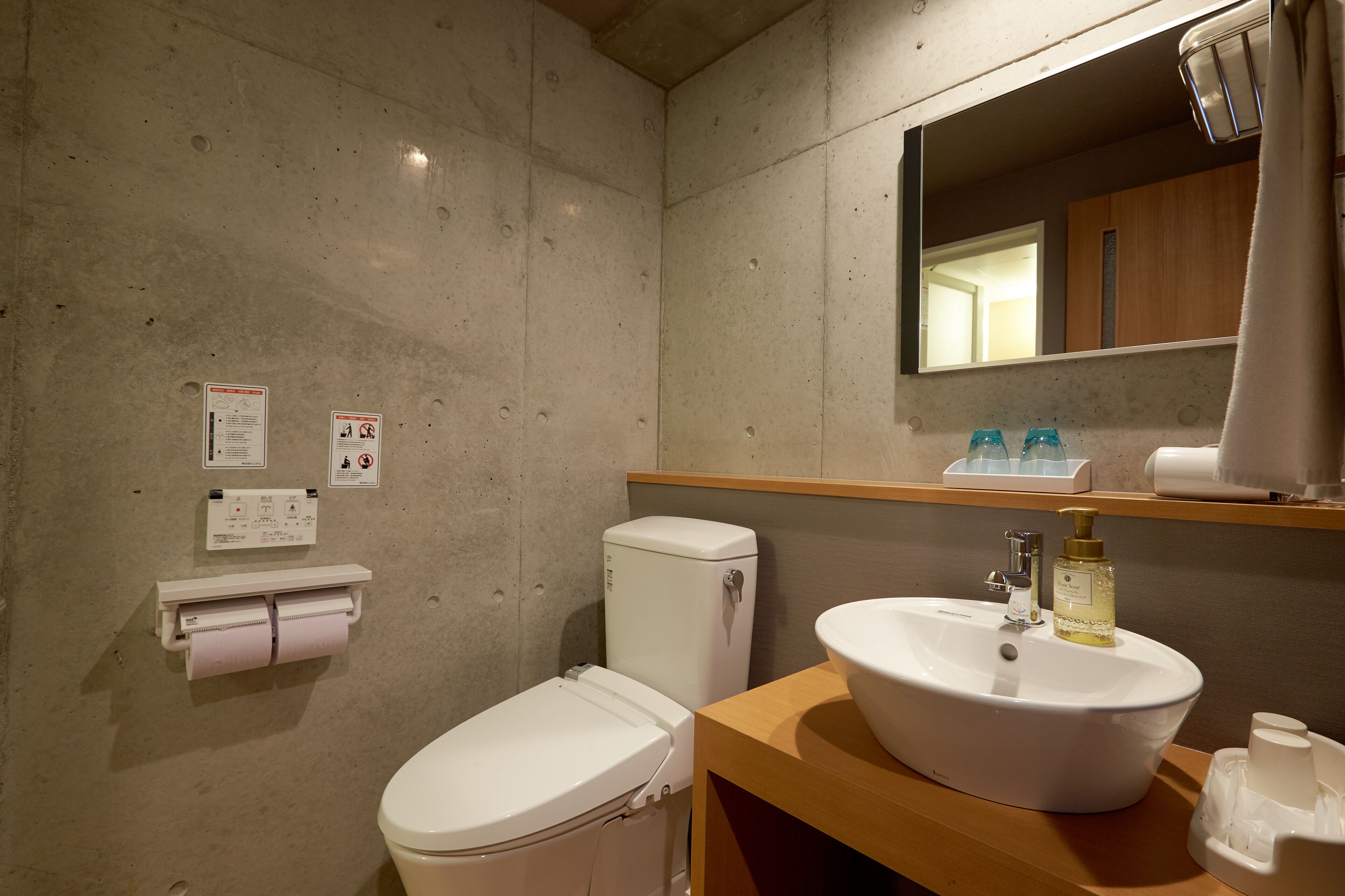 Un baño con inodoro, lavamanos, espejo y secador de manos.