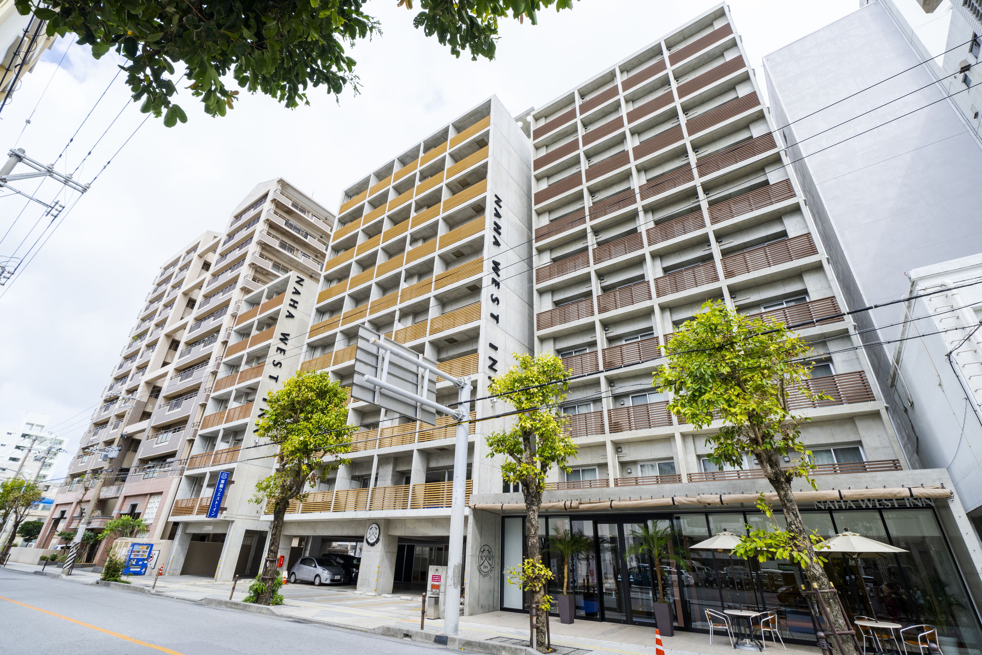 A multi-story hotel with a modern design, featuring balconies, a ground-level cafe, and a visible entrance.