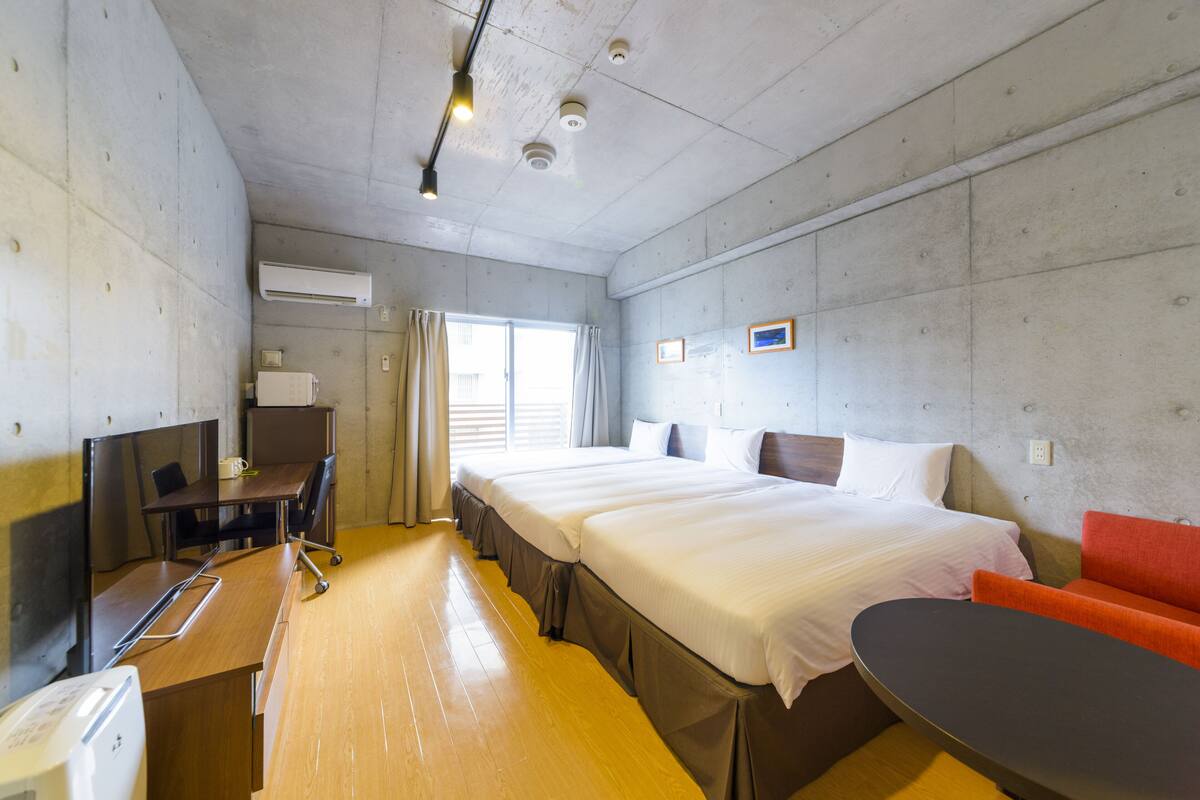 A hotel room with a large bed, a desk with a chair, a TV, and a small table.