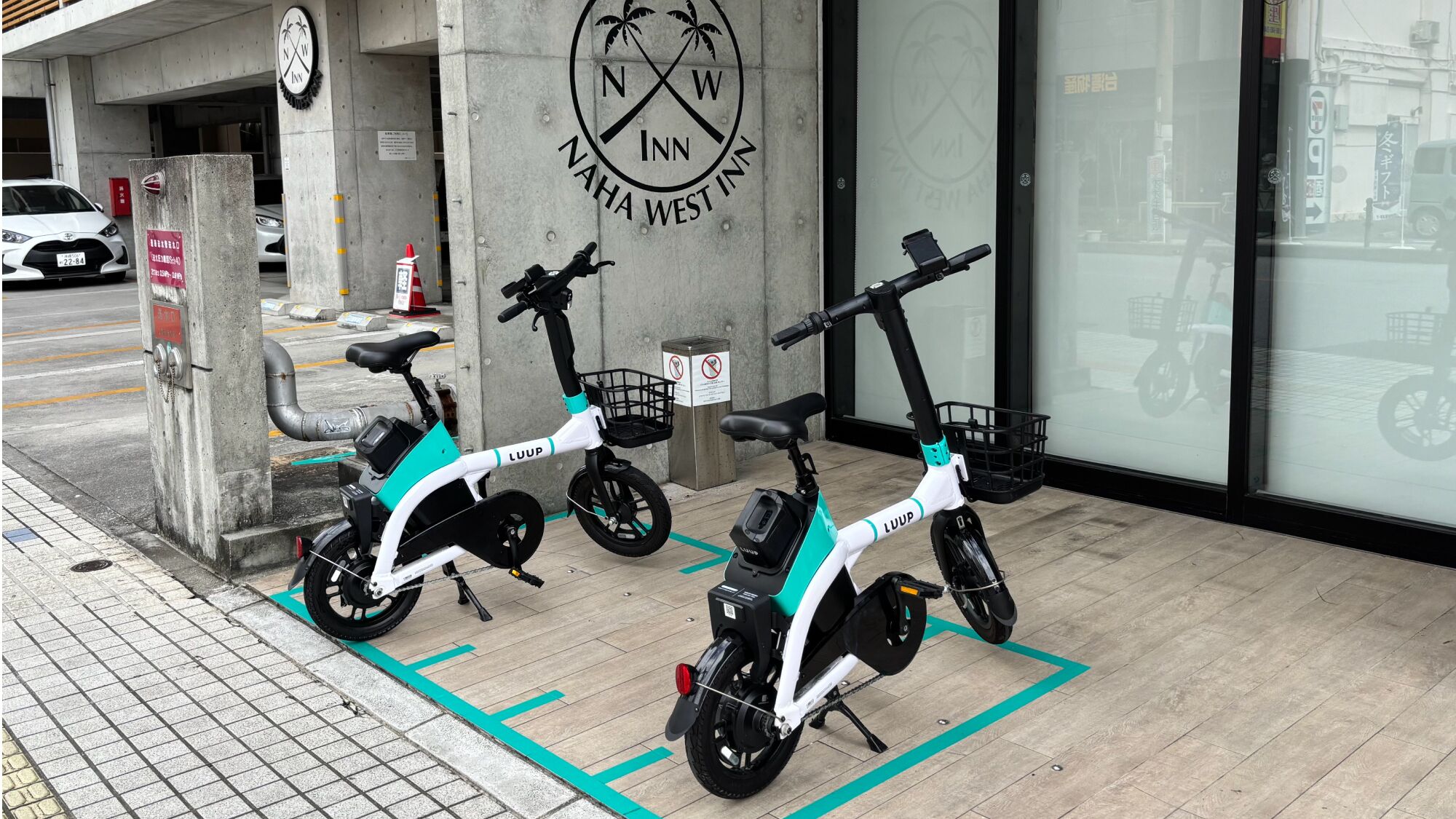 Two electric scooters parked in front of a building with a sign reading 'NWA West Inn.'