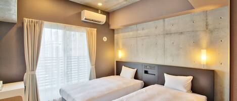 A hotel room with two beds, a desk, and a large window with curtains.