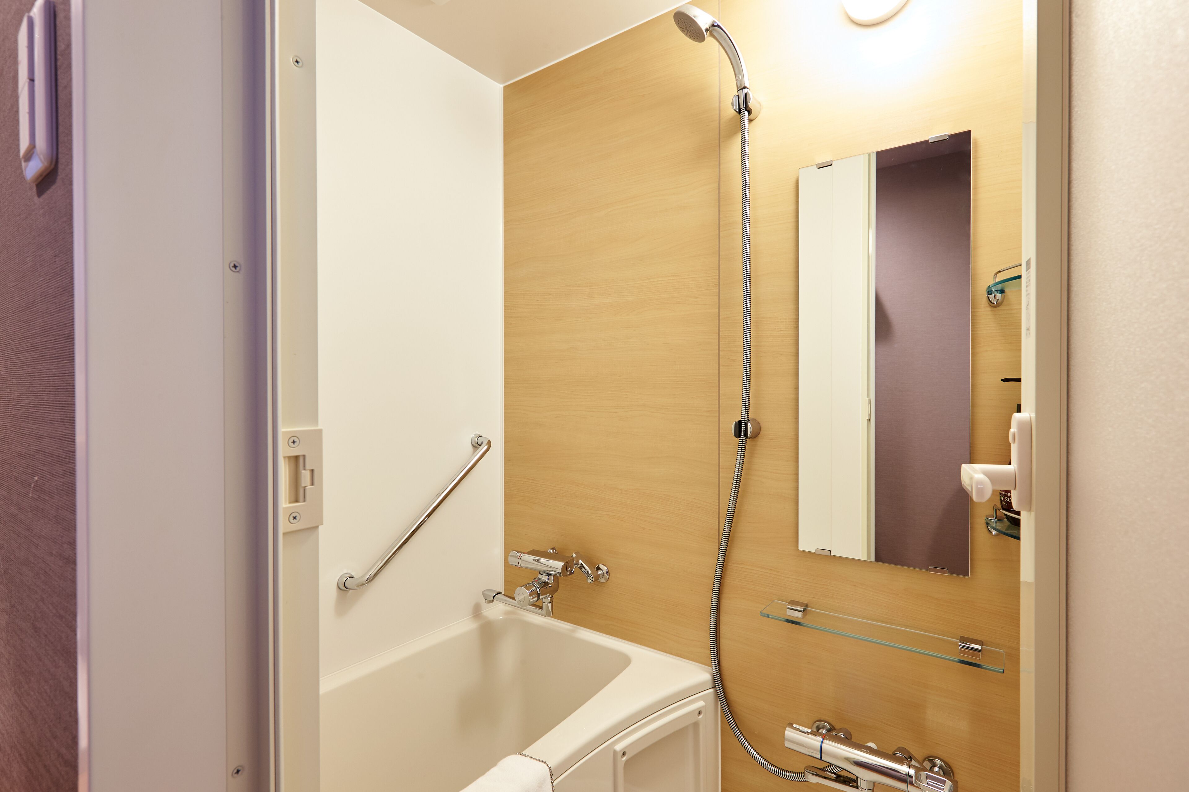 Een moderne badkamer met een bad, een douche en een glazen plank.