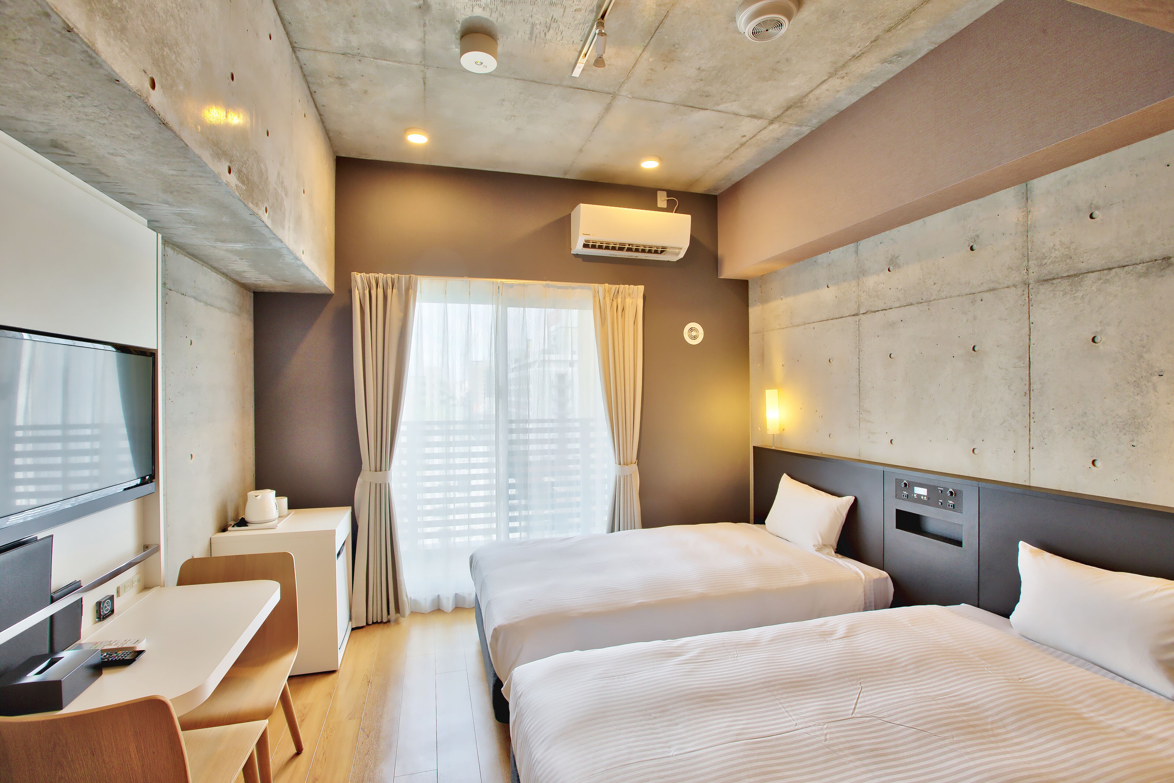Une chambre d’hôtel avec deux lits, un bureau, une télévision et un appareil de climatisation.