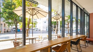 Un café al aire libre con mesas y sillas, sombrillas grandes y vistas a la calle.