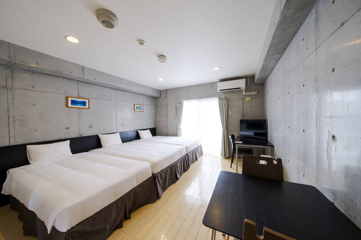 A hotel room with two beds, a desk, and a TV.