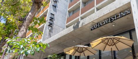 A building with a sign reading "NAHAWEST INN" and outdoor seating with umbrellas.