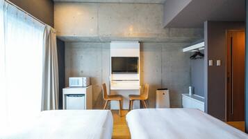 A modern hotel room with two beds, a desk, a chair, a microwave, and a wardrobe.
