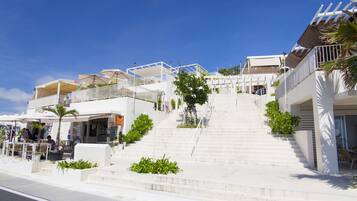 A staircase leading to a white building with outdoor seating and umbrellas.