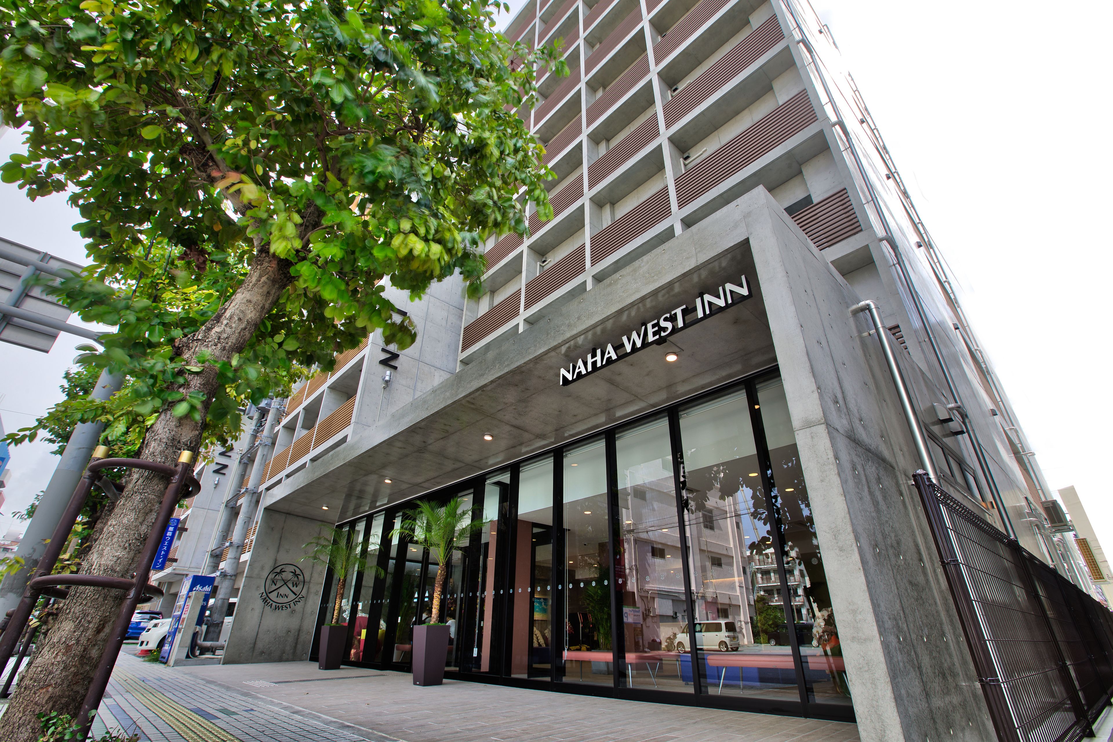 A modern building with a large glass facade and the name "NAHA WEST INN" prominently displayed.