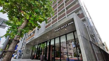 A modern building with a large glass facade and the name "NAHA WEST INN" prominently displayed.