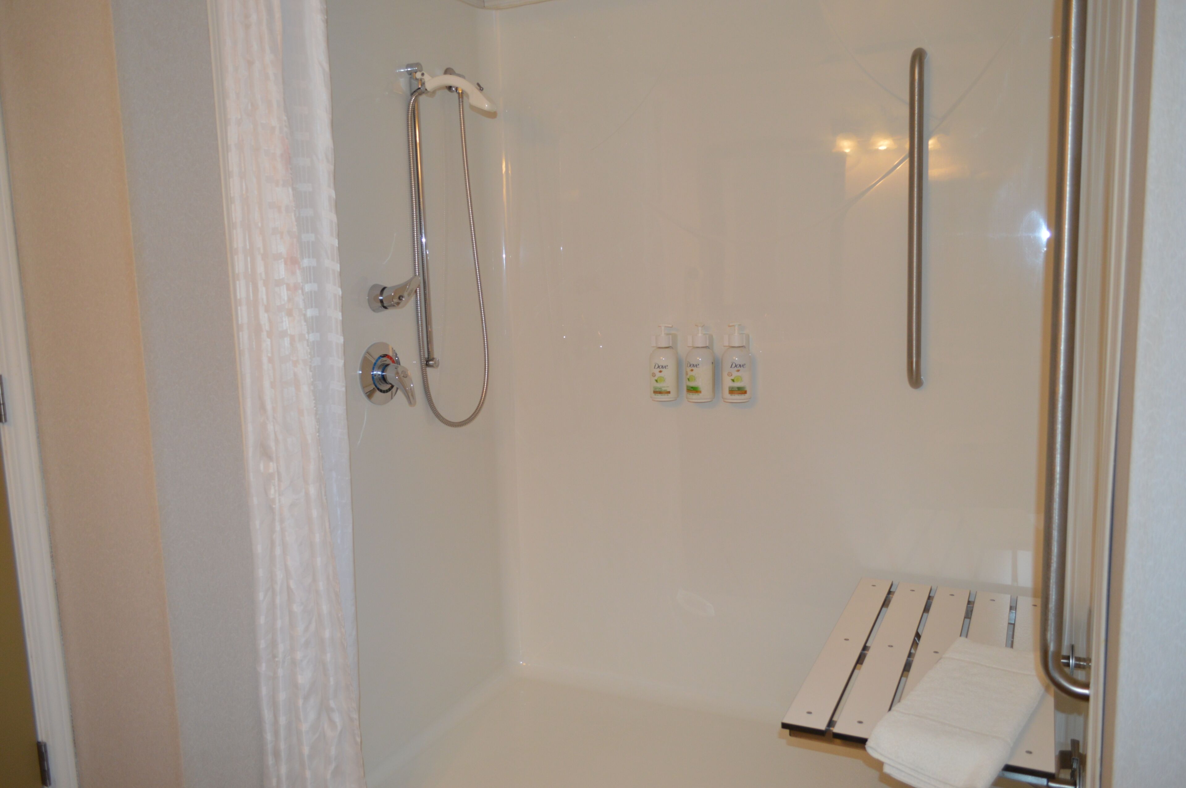 A shower with a handheld showerhead, a glass-enclosed shower area, and a towel rack with a folded towel.