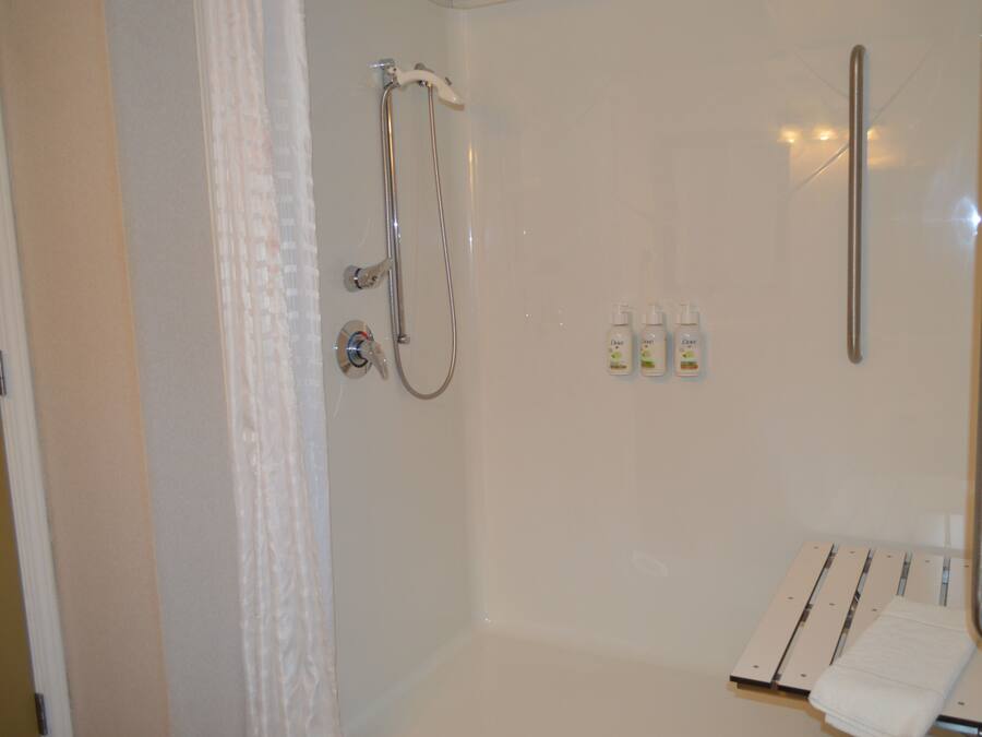 A shower with a handheld showerhead, a glass-enclosed shower area, and a towel rack with a folded towel.