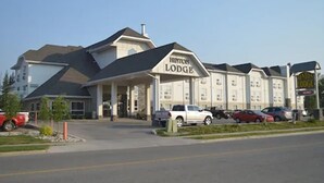 Edifício do Hinton Lodge com entrada coberta, vários espaços de estacionamento e céu claro.