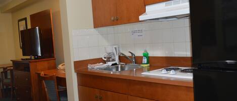 A compact kitchen with wooden cabinets, a sink, a stove, and a refrigerator.