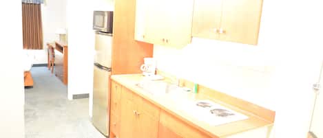 A compact kitchen with wooden cabinets, a microwave, a sink, and a stove.