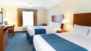 Quarto de hotel com duas camas, uma escrivaninha, uma cadeira e uma televisão.