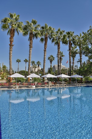 Una piscina al aire libre, sombrillas, sillones reclinables de piscina