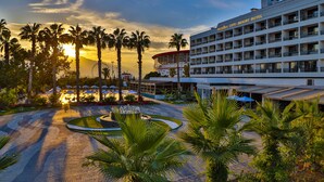 Un hotel resort con piscina, palmeras y vistas al atardecer.