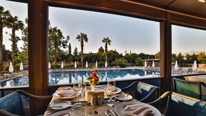 Mesa para dos con vistas a una piscina y palmeras.