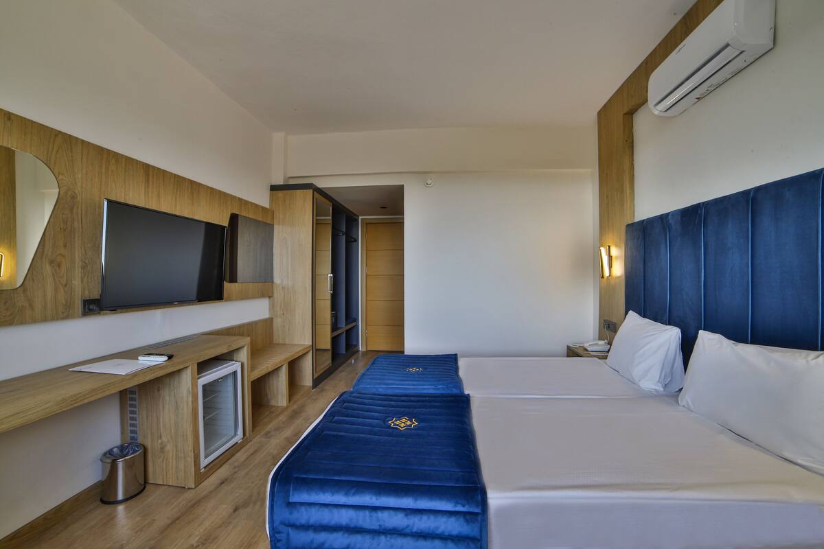 A hotel room with a bed, a TV, a desk, and a wardrobe.