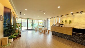 A reception area with a wooden reception desk, white chairs, potted plants, and a glass door leading outside. - Finders Hotel Hualien Da-Tong (Hualien City)