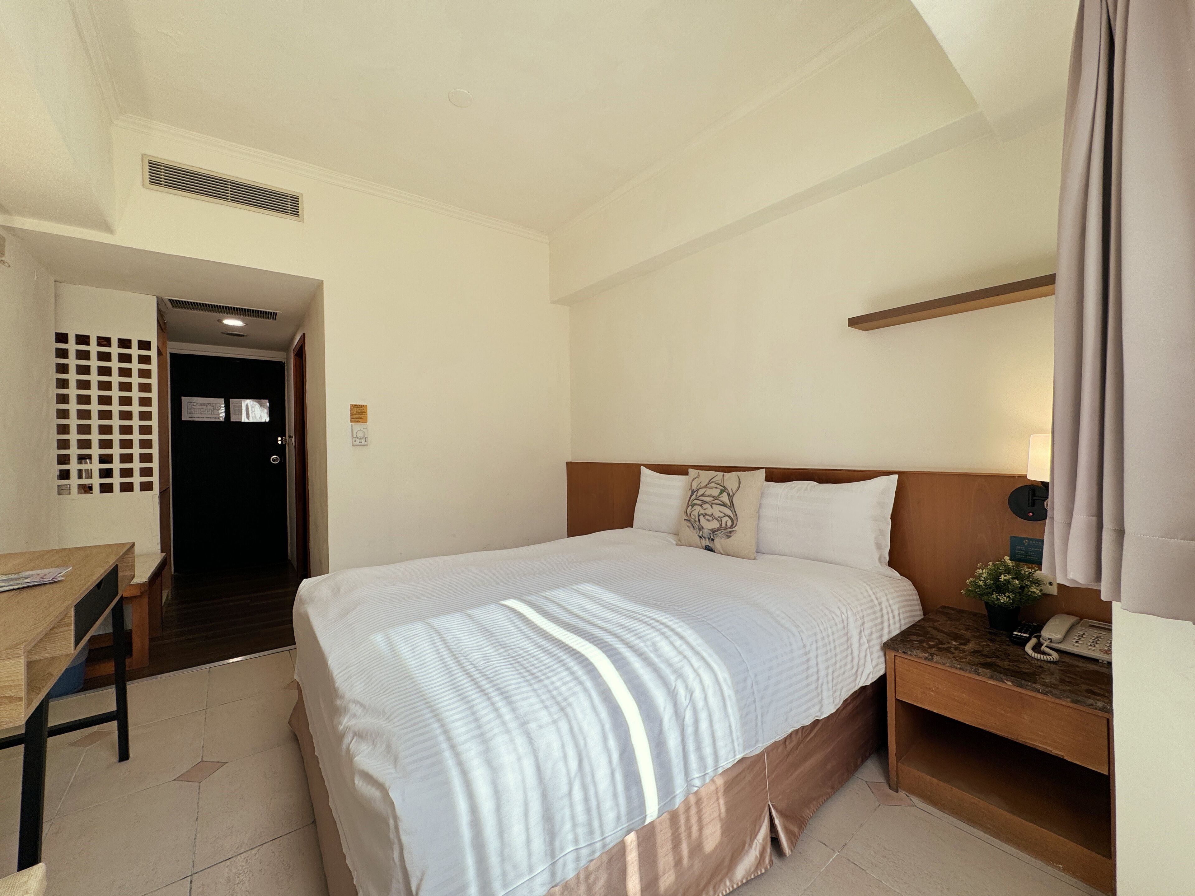 Una habitación de hotel con cama, mesita de noche y escritorio con silla.
