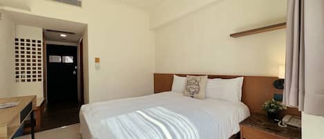 Una habitación de hotel con cama, mesita de noche y escritorio con silla.