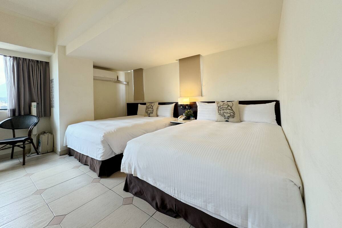 Habitación de hotel con dos camas, un escritorio y una silla.