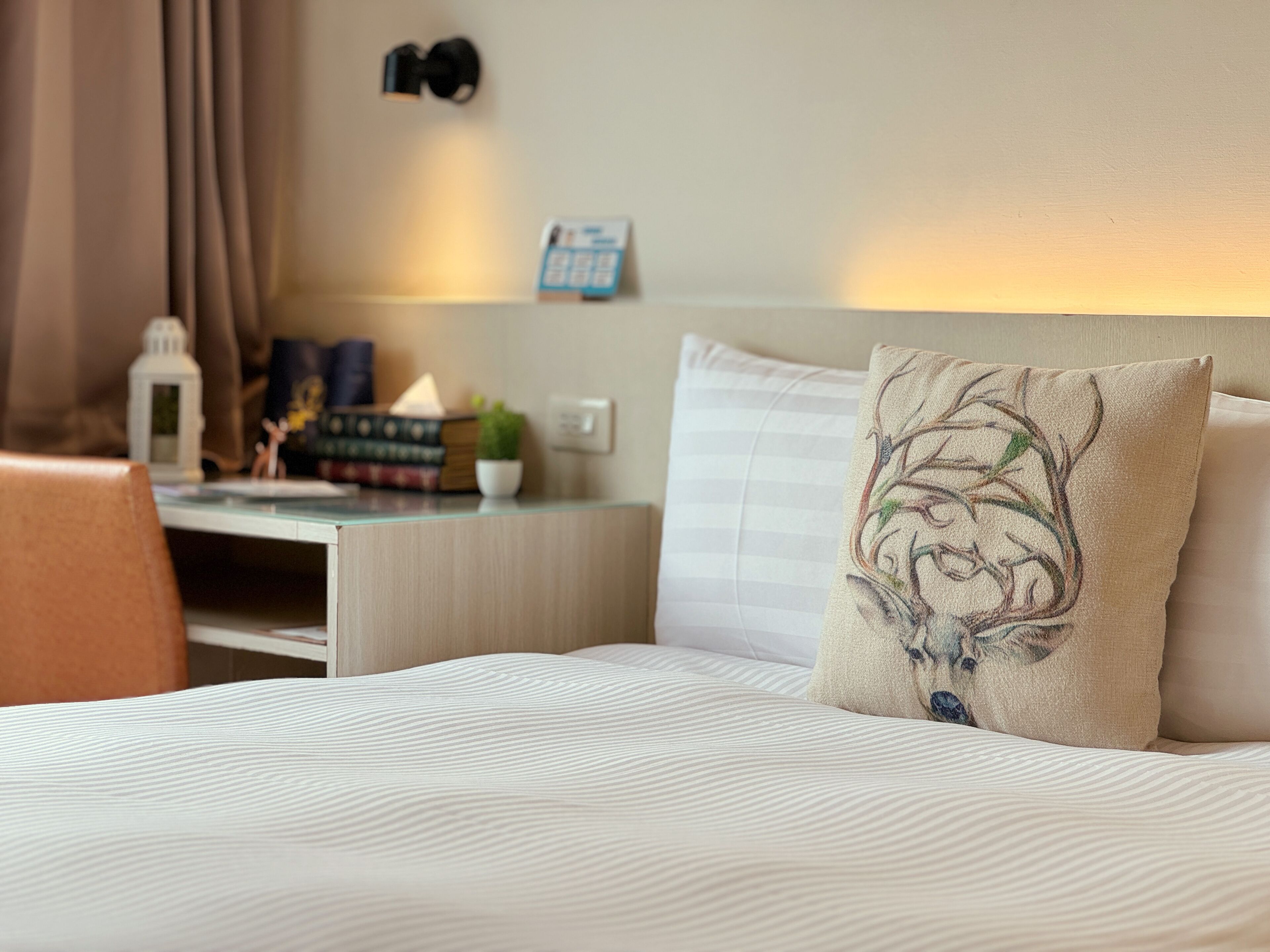 A neatly arranged hotel room with a bed, a desk, and a chair.