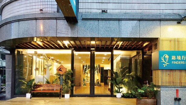 A building entrance with a wooden bench, potted plants, and a sign with Chinese characters. - Finders Hotel Hualien Da-Tong (Hualien City)