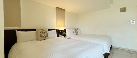 A hotel room with two beds, a nightstand with a lamp, and a wall-mounted mirror.