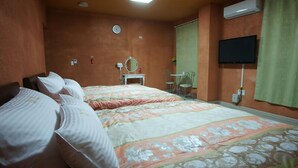 Un dormitori amb dos llits, una taula de nit amb mirall, un televisor fixat a la paret i un aparell d'aire condicionat.
