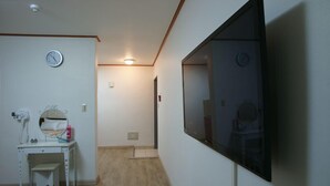 Una habitació amb escriptori blanc, mirall i televisió penjada.